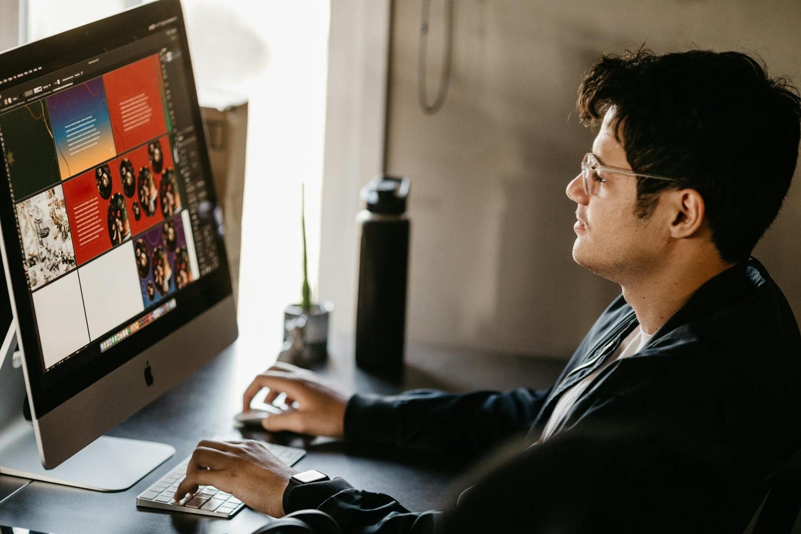Graphic designer working at an iMac displaying a colorful brand layout