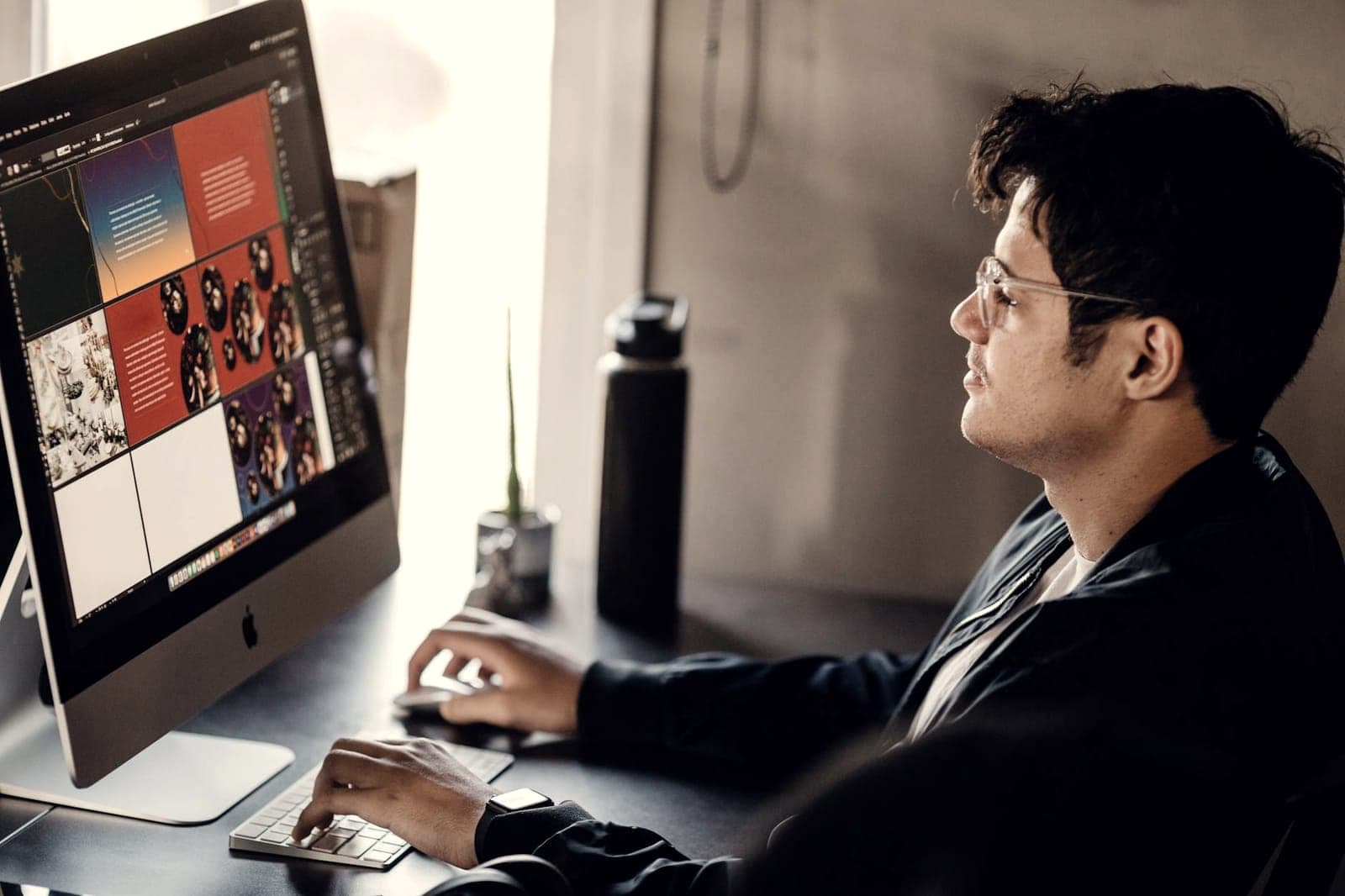 Graphic designer reviewing a colorful brand layout on an iMac