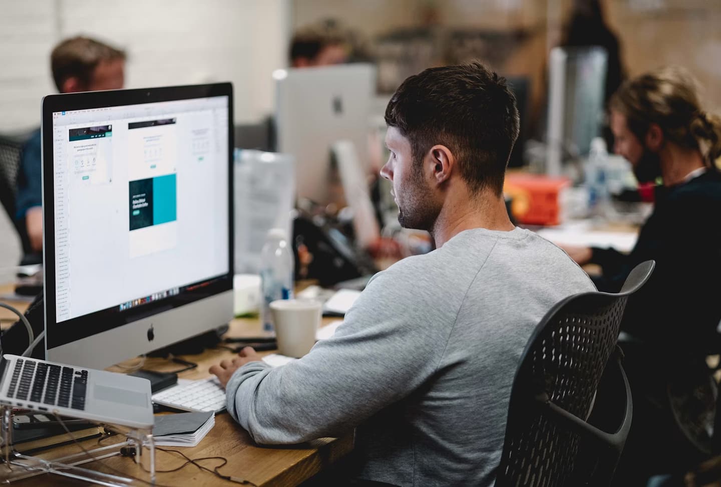 A designer reviewing creative work at their desk in a busy studio
